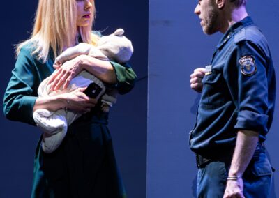 Deux comédiens se faisant face un en policier et une femme tenant un bébé