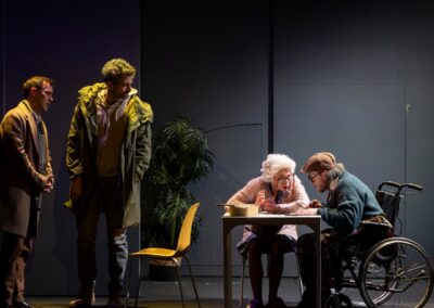 Quatre comédiens sur scène deux debout les deux autre assis à une table